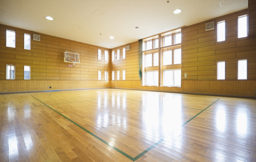 内観写真。体育館のような部屋で、床がコートになっておりバスケットゴールが見えている。窓から光がさし込んでいる。