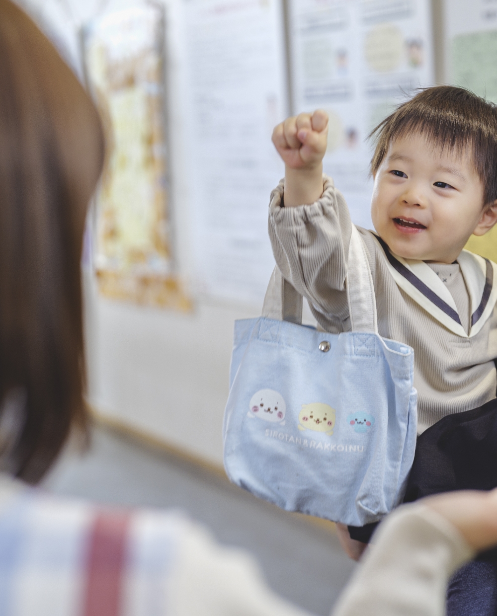 お母さんに抱っこされながら児童館職員に手を振る赤ちゃんの写真